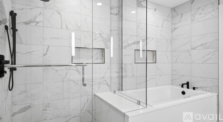 A white bathroom with a marble tile wall and a white bathtub.