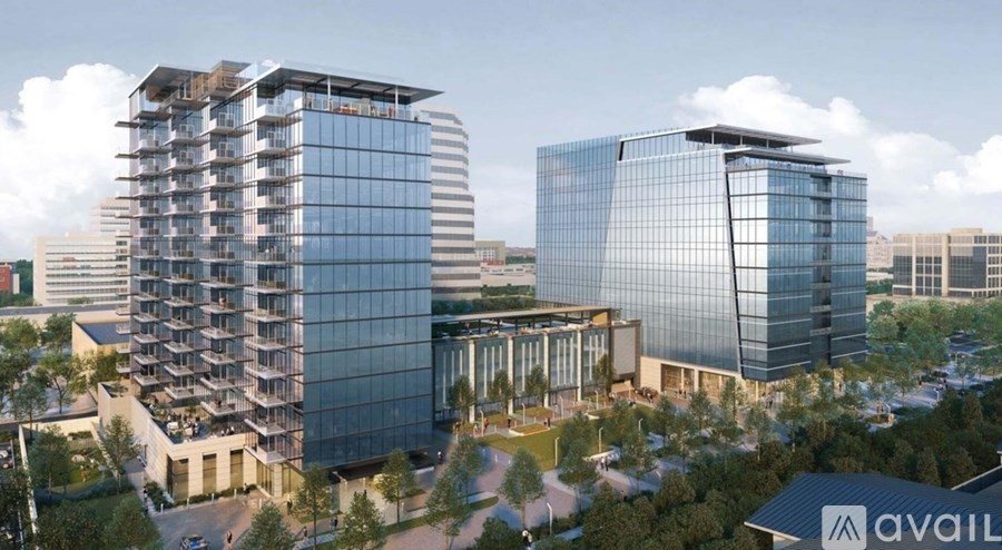 Two modern glass buildings with a parking lot in front.