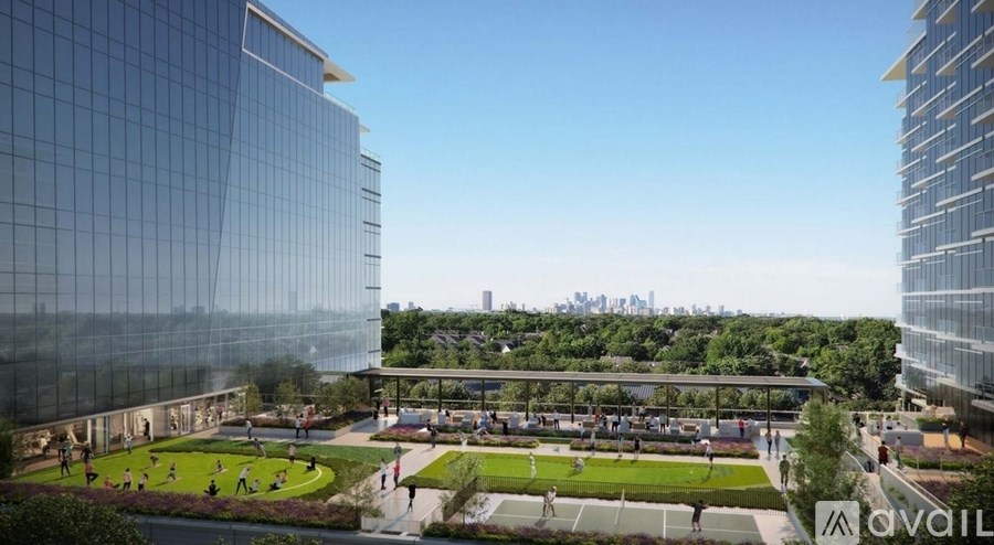 A modern glass building with a green park in front.