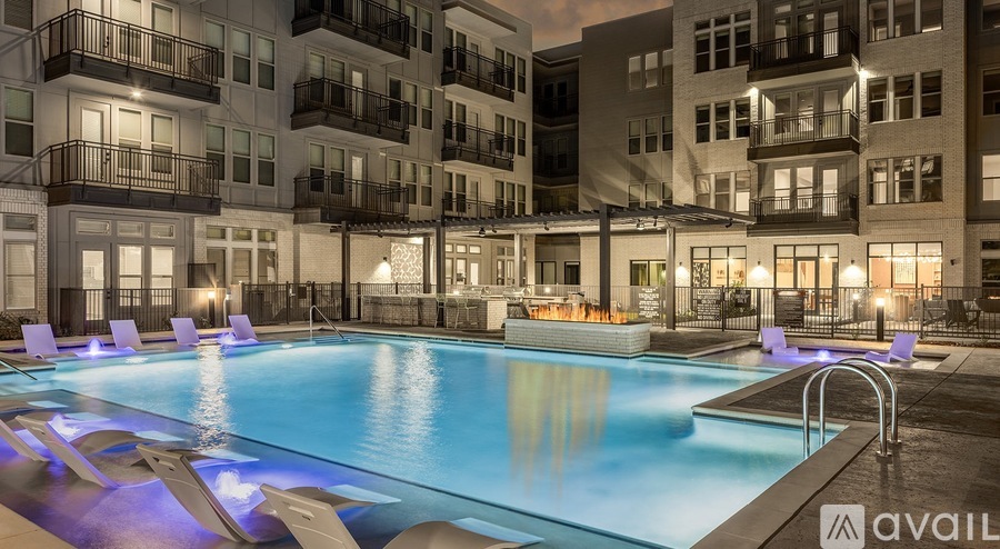 A large swimming pool in front of apartment buildings at night.