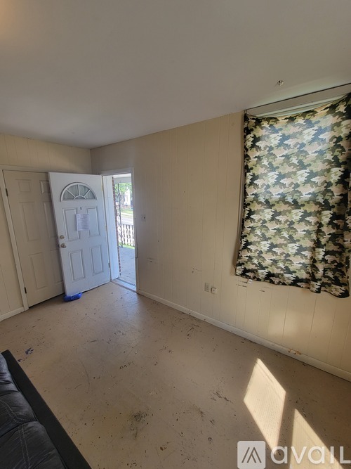 A room with a door and a window with a floral curtain.
