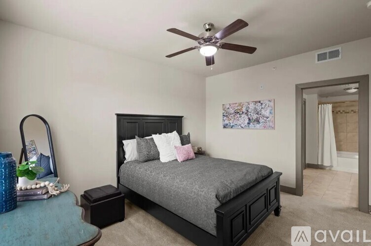 A bedroom with a bed, a ceiling fan, and a side table.