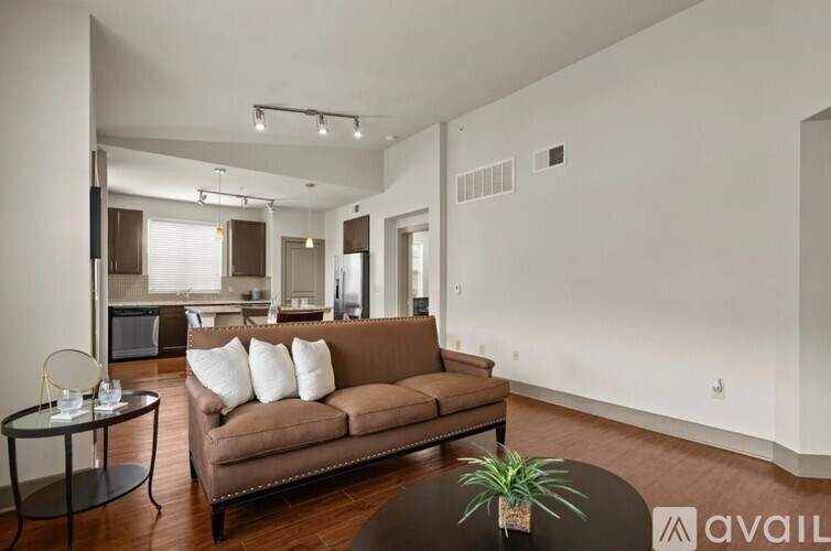 A living room with a brown couch and a glass table.