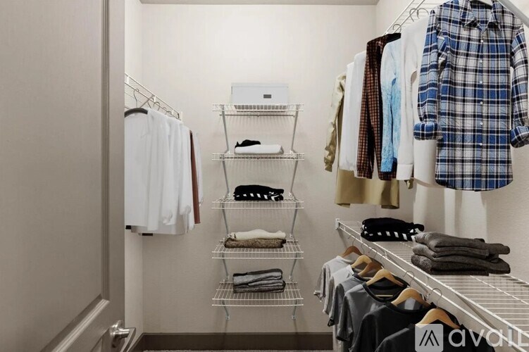 A white wall with clothes hanging and shelves with clothes and a white air conditioner.