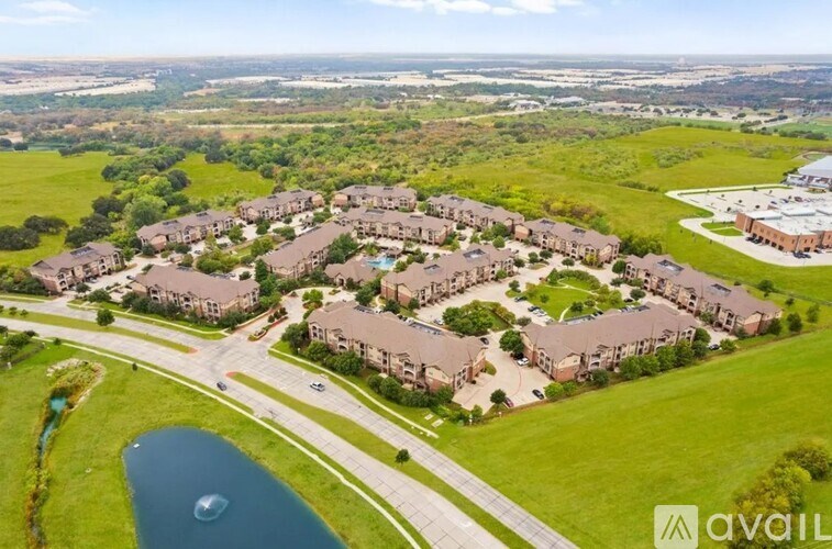 A bird's eye view of a housing complex with a lake in the foreground.