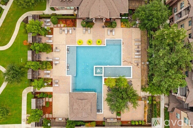 An aerial view of a swimming pool surrounded by a garden and a house.