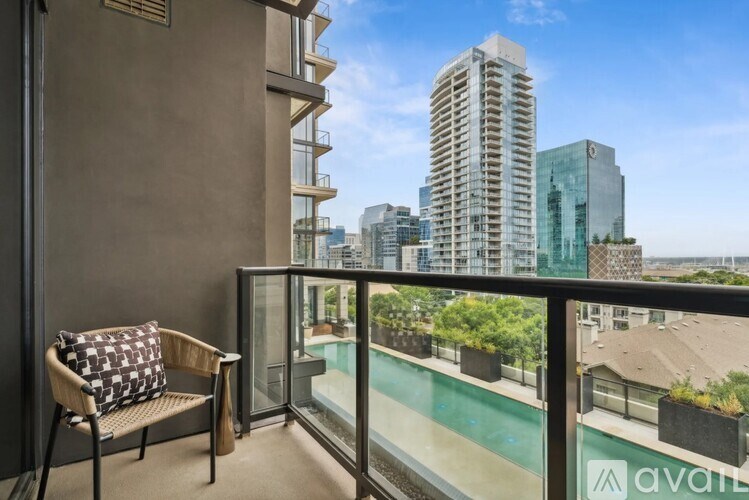A balcony with a chair and a pillow with a view of the city.