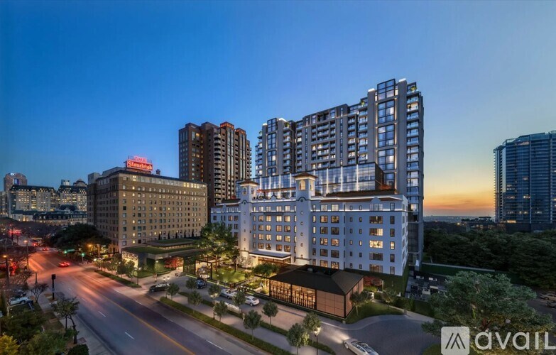 A cityscape at dusk with a road leading to a large building with the logo "avail" on it.