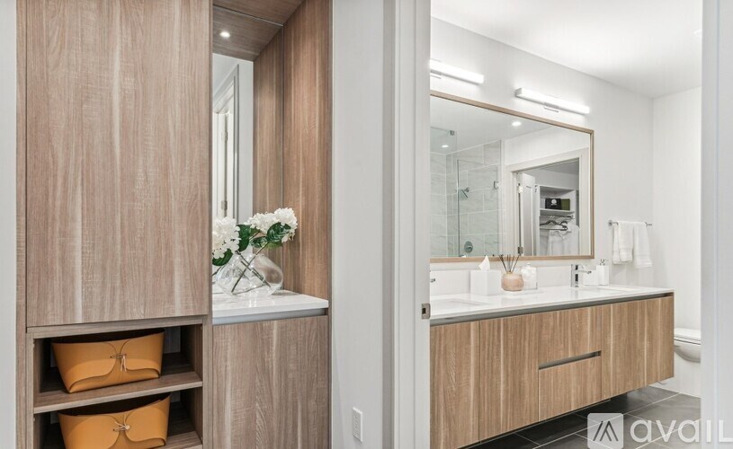 A bathroom with a vanity, mirror, and shelves with storage baskets.