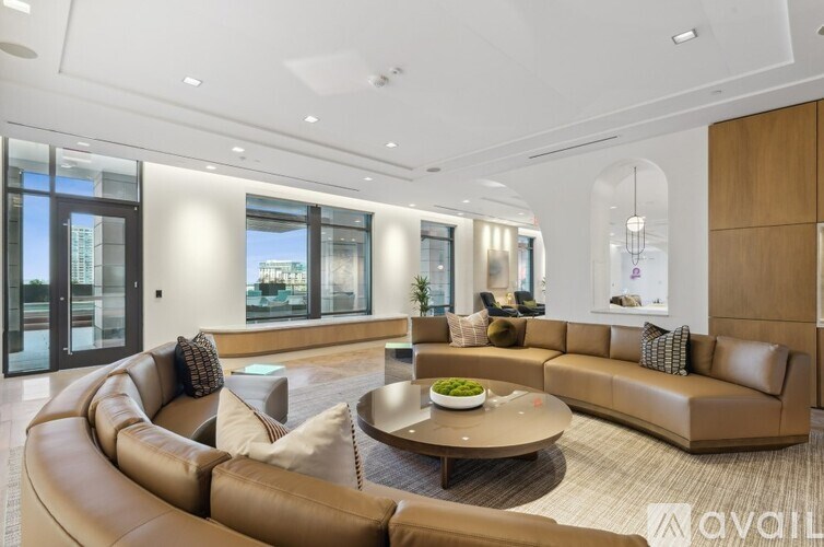 A modern living room with a large brown leather sofa and a coffee table in the center.