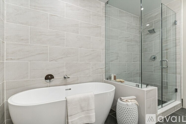 A white bathtub sits in a bathroom with a glass shower door.