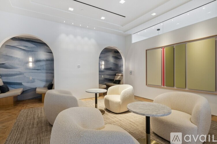 A modern waiting room with white chairs and a large window.