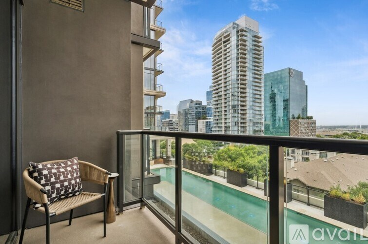 A balcony with a chair and a pillow with a view of the city.