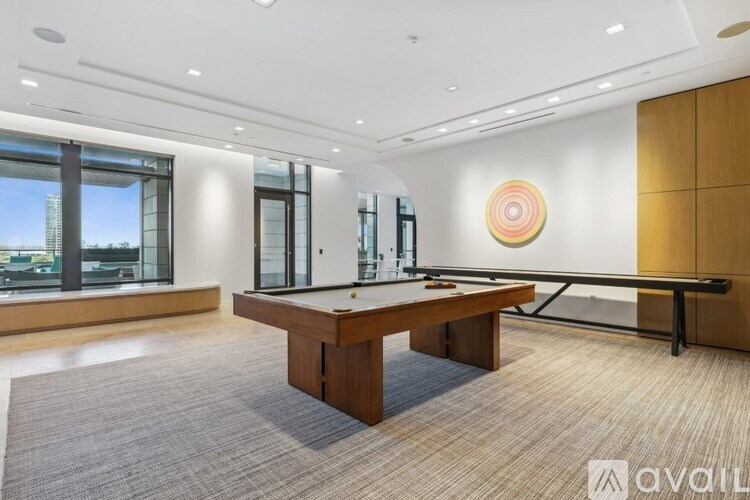 A room with a pool table and a window overlooking a cityscape.