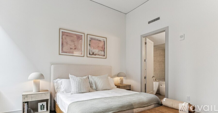 A bedroom with a bed, two lamps, and two pictures on the wall.