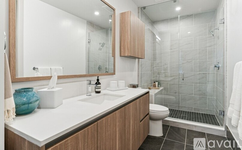 A modern bathroom with a white countertop and a glass-enclosed shower.