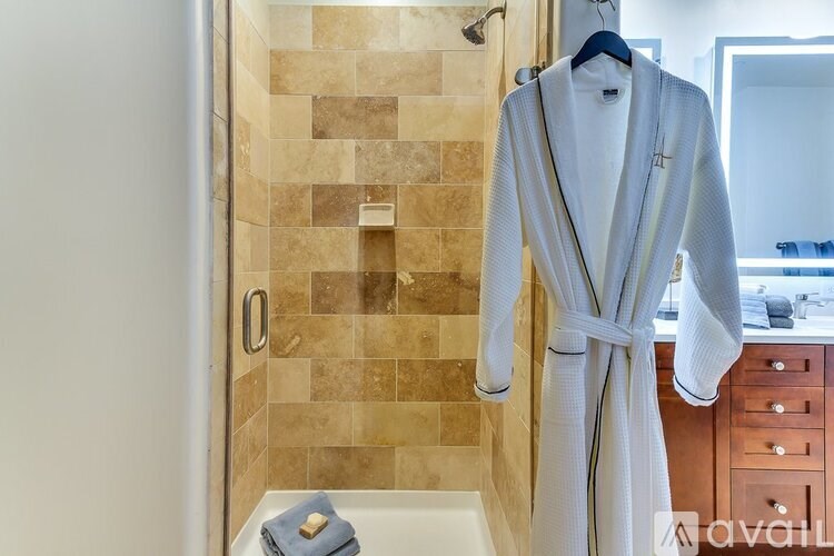 A white robe is hanging on a hanger in a bathroom.