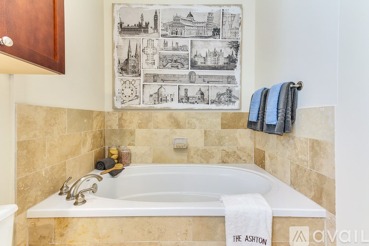 A bathroom with a large tub and a picture of various buildings on the wall.