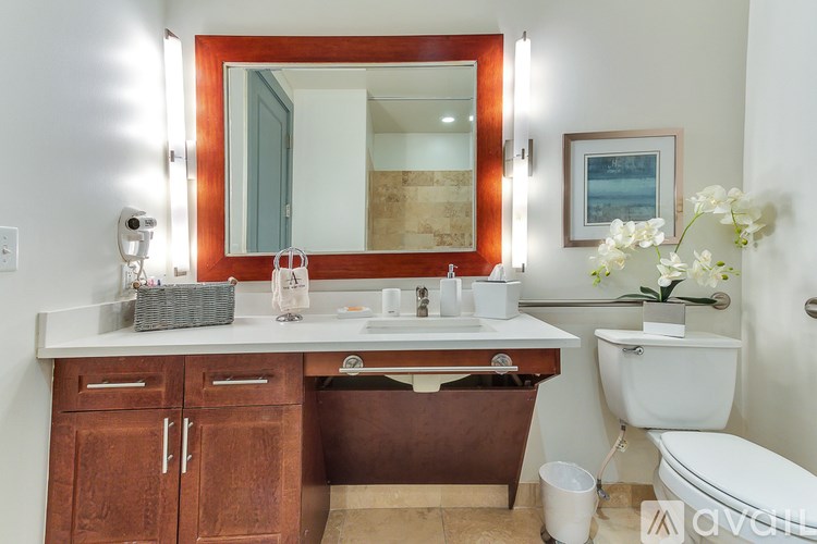 A bathroom with a white toilet, a sink with a mirror above it, and a brown cabinet below the mirror.