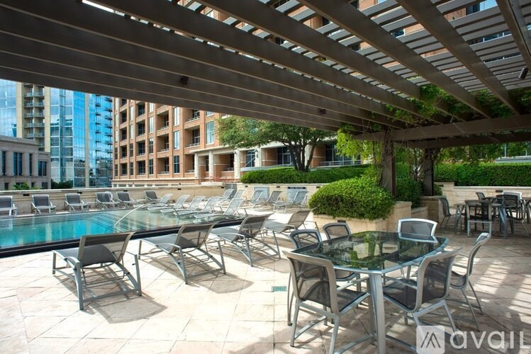 A pool area with chairs and tables under a wooden pergola.