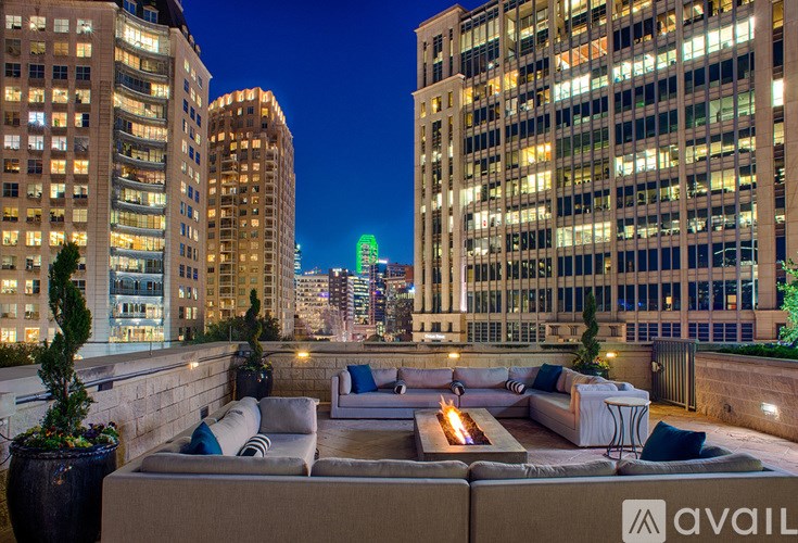 A rooftop patio with a couch and pillows overlooking a city at night.