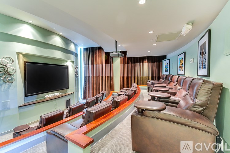 A long row of brown leather chairs are lined up in a room with a television on the wall.