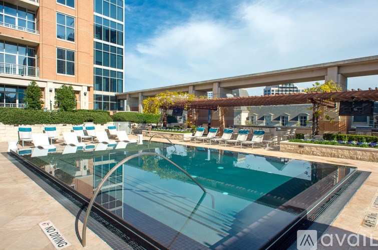 A pool with chairs around it and a building in the background.