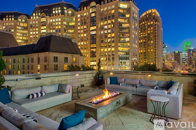 A patio with a fire pit and seating area in front of a city skyline.