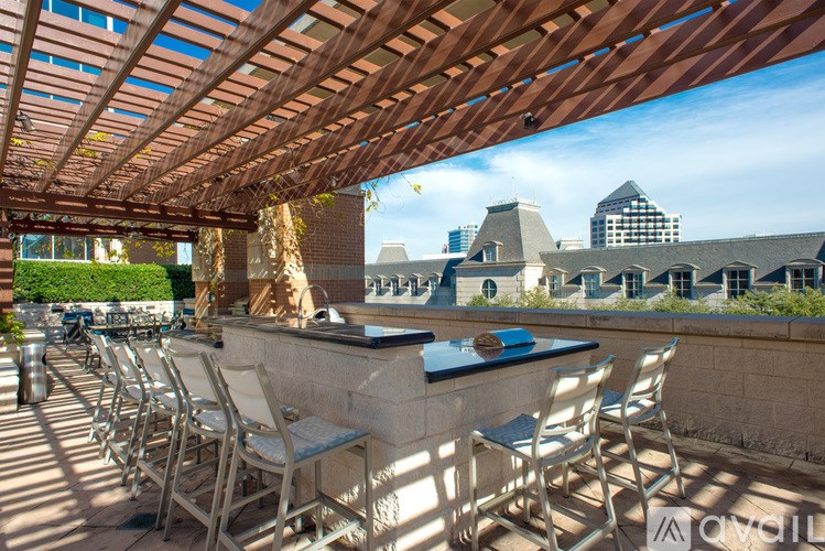 A patio with a bar and chairs under a wooden roof.