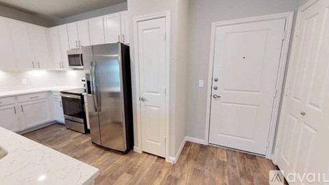 A kitchen with white cabinets and a stainless steel refrigerator.
