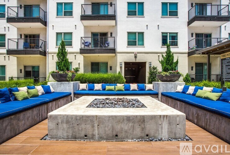 A modern courtyard with a fire pit and seating area in front of a white apartment building.
