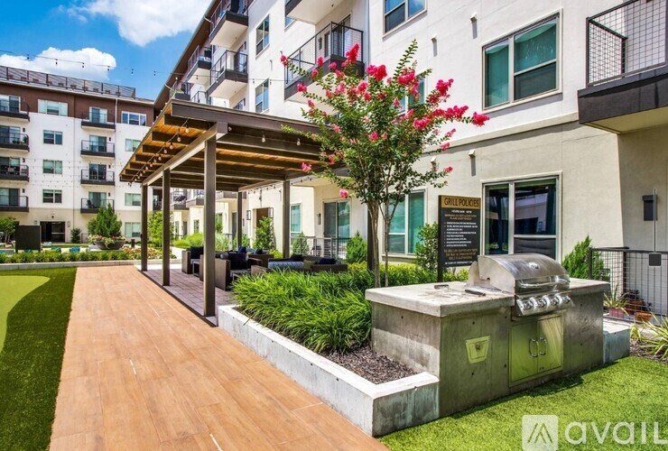 A patio area with a grill and a tree with red flowers.