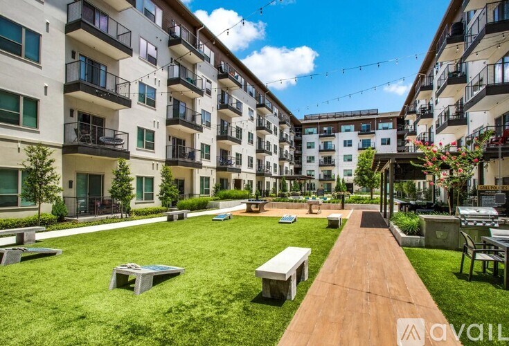 A sunny day at a modern apartment complex with a wooden walkway and green lawns.