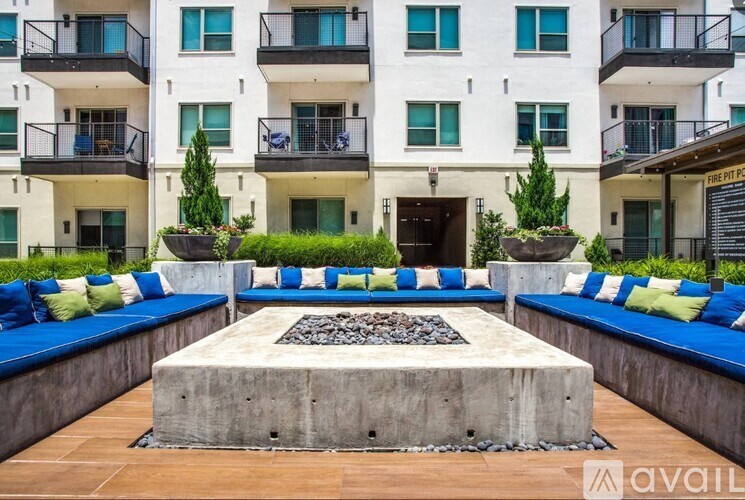 A courtyard with a fire pit surrounded by blue cushioned seating.