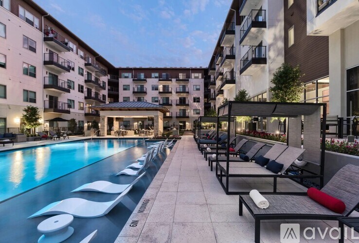 A pool area with sun loungers and a building in the background.
