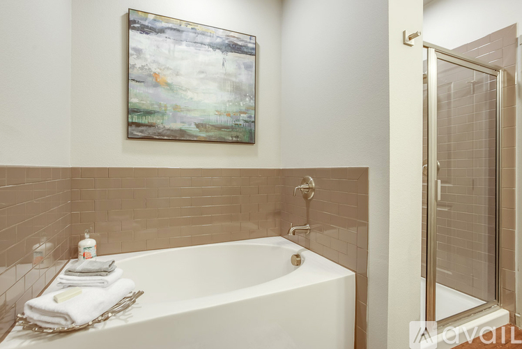 A bathroom with a white tub and a painting on the wall.