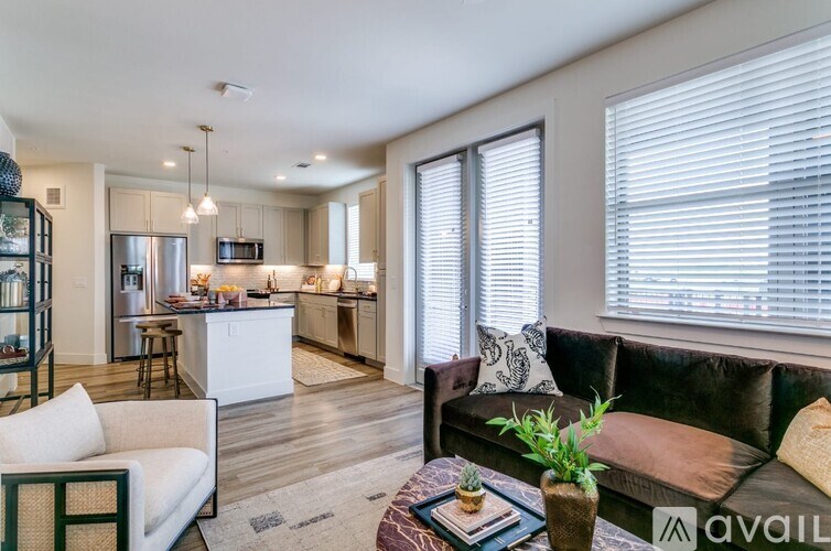 A modern living room with a brown couch and a kitchen in the background.