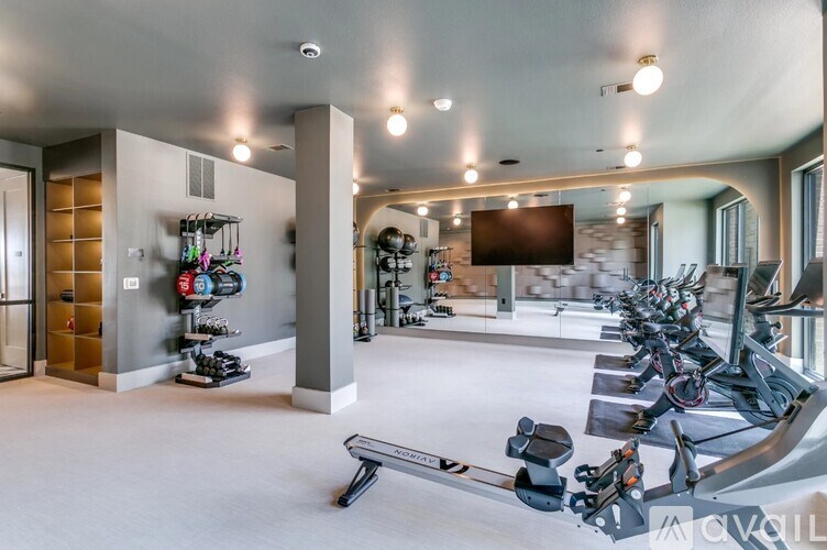 A gym with a row of treadmills and a television.