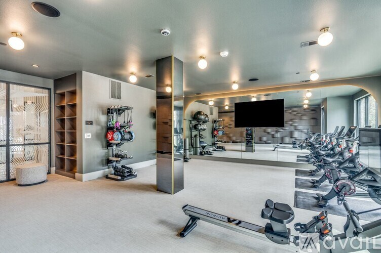 A modern gym with a variety of equipment including treadmills, weights, and a television.