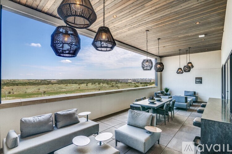 A modern outdoor living space with grey furniture and hanging lights.