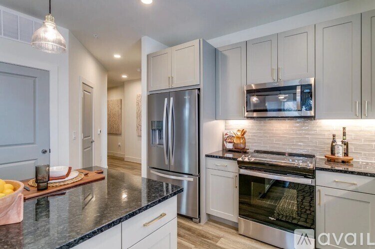 A modern kitchen with a black countertop and stainless steel appliances.
