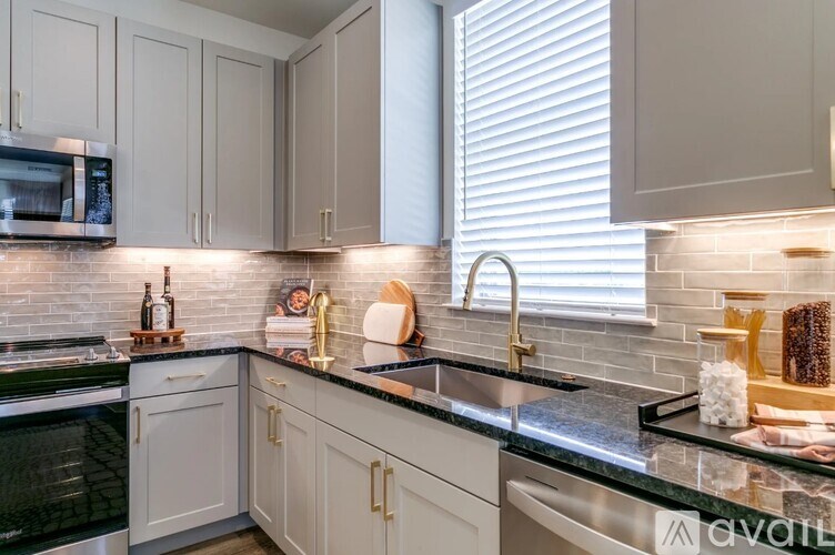A kitchen with white cabinets and a black countertop.