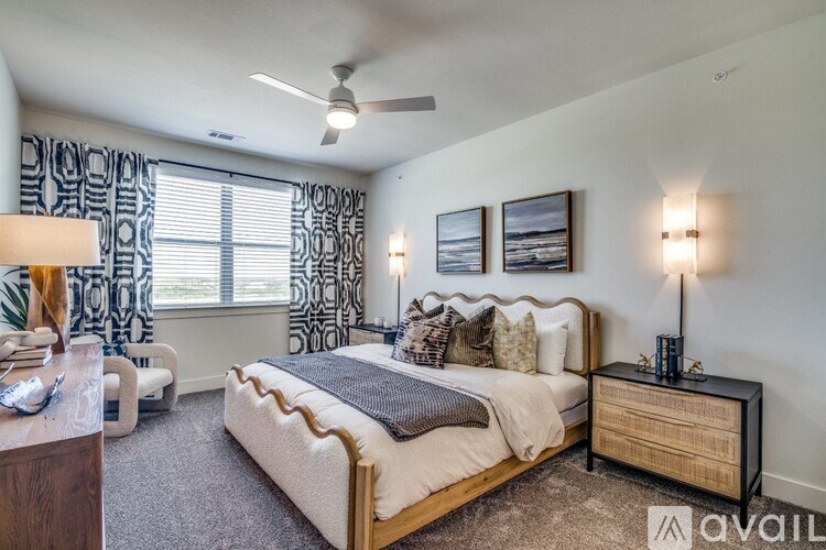 A bedroom with a large bed, a ceiling fan, and two pictures on the wall.