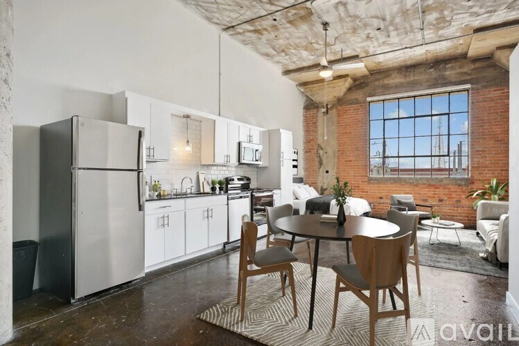 A kitchen with a table and chairs in the foreground and a window with a view of a building in the background.
