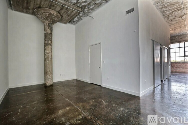 A large empty room with a concrete pillar and a wooden ceiling.