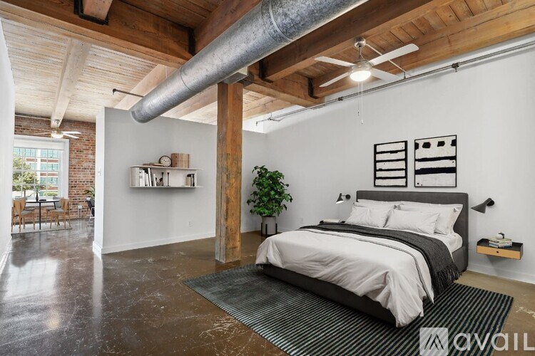 A bedroom with a large bed and a plant on the side table.