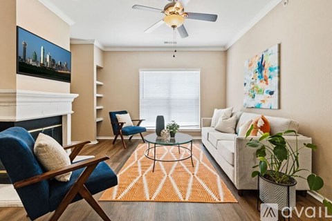 A living room with a blue chair, a white couch, and a painting on the wall.
