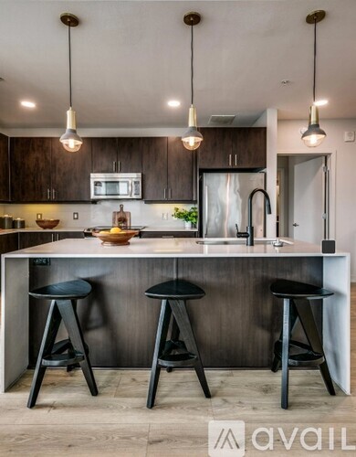 A modern kitchen with a white countertop and black bar stools.