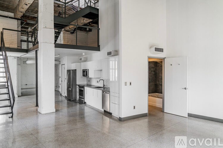A large open kitchen and living space with white walls and a staircase.