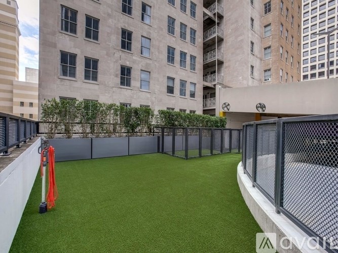 A small fenced-in area with artificial grass in the middle of a city.